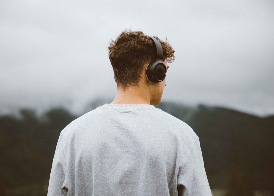 Homme vu de dos portant un casque audio dans un paysage brumeux