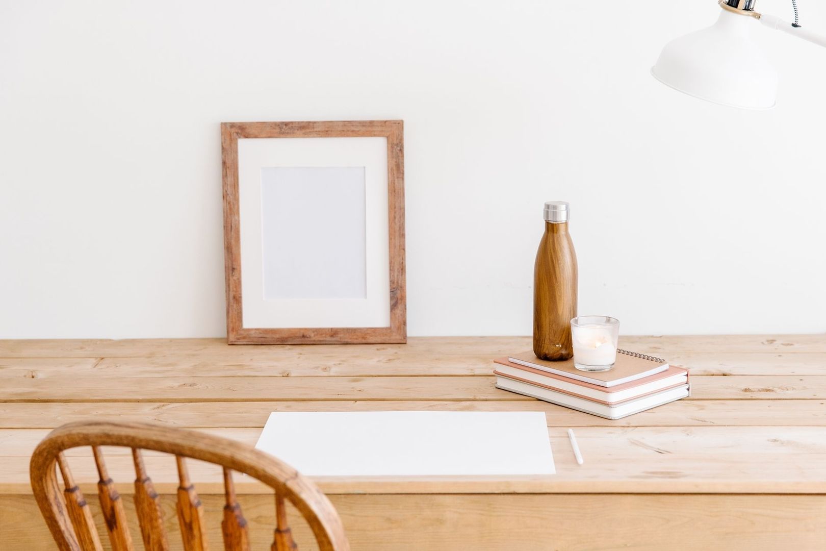Bureau en bois épuré avec livres, bouteille et bougie dans un espace calme