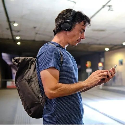 Homme portant un casque audio et consultant son téléphone dans une gare